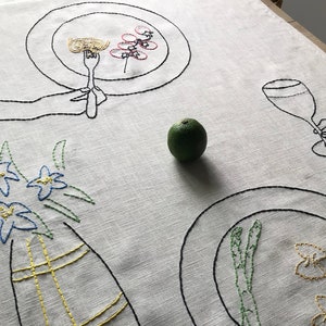 Hand-embroider dinner for two beige linen table runner with plates, italian pasta and vegetables, vase with flowers, glass of wine