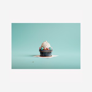 May include: A white cupcake with blue and pink frosting and gold sprinkles on a white paper doily on a light blue background.