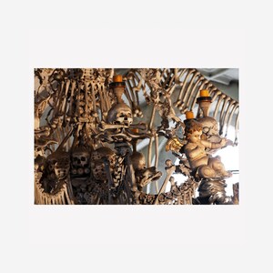 Pode incluir: Um candelabro feito inteiramente de ossos humanos, com uma figura de querubim no centro. O candelabro é decorado com crânios e outros elementos esqueléticos.