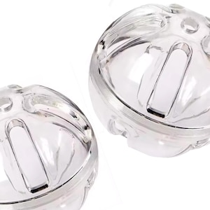 May include: Two clear, spherical objects with a cage-like design. Each sphere has a series of curved, rectangular openings and small circular holes. The transparent material allows light to pass through, creating a bright, clean appearance.