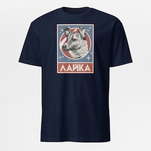 以下が含まれることがあります： 紺色のTシャツに、赤と青の枠の中に犬のライカのヴィンテージスタイルのイラストが描かれています。枠の下には「ЛАЙКА」という文字が印刷されています。