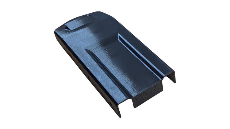 May include: A black, rectangular object with a textured surface. The object has a curved top and a recessed channel running along its length. The ends are cut out, and it appears to be made of a rigid material.