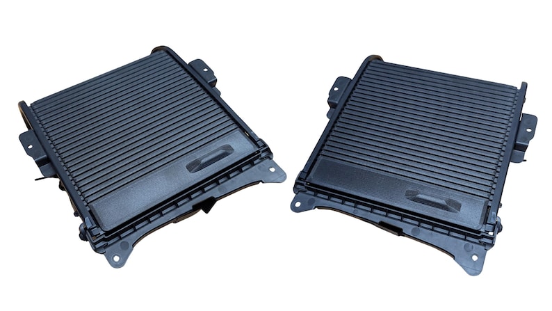 May include: Two black plastic car console storage compartments. Each compartment has a rectangular shape with a ridged top and a small recessed handle. The compartments are designed to fit into a vehicle's interior.