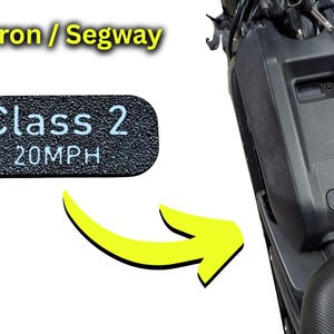 Könnte beinhalten: Ein schwarzer rechteckiger Aufkleber mit dem weißen Text "Class 2 20MPH" wird neben einem schwarzen Elektroroller gezeigt. Der Aufkleber ist für Surron- und Segway-Modelle konzipiert.