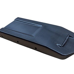 May include: A black, rectangular object with a slightly curved top and a raised section. The object has a series of small holes along one side and a white outline. The item is set against a white background.