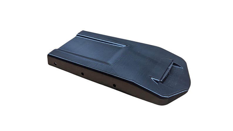 May include: A black, rectangular object with a slightly curved top and a raised section. The object has a series of small holes along one side and a white outline. The item is set against a white background.