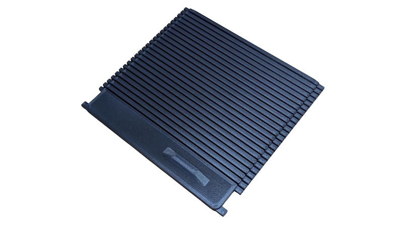 May include: A dark blue, rectangular, ridged object with a handle-like extension. The object has a series of parallel lines across its surface. The handle-like extension has a design etched into it.