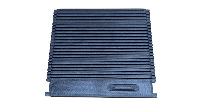 May include: A dark blue, rectangular object with a series of parallel, horizontal ridges. The object has a recessed handle on one end and appears to be made of a rigid material. The design suggests a functional item, possibly a cover or a tray.