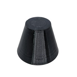 Op de afbeelding: Een zwarte, kegelvormige dop van rubber met een getextureerd oppervlak.