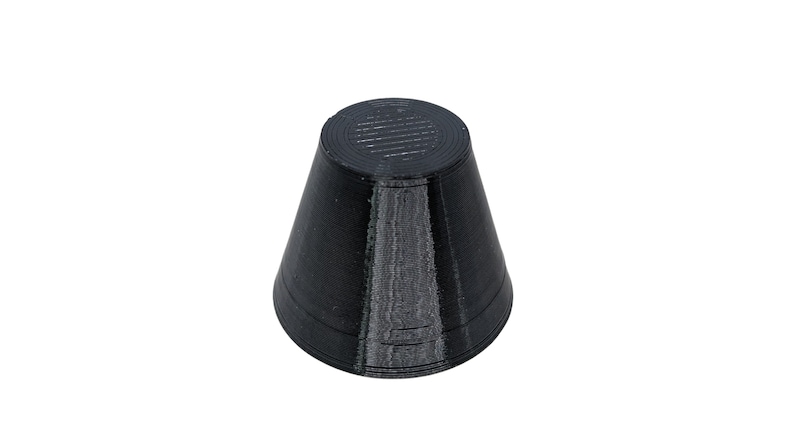 Op de afbeelding: Een zwarte, kegelvormige dop van rubber met een getextureerd oppervlak.