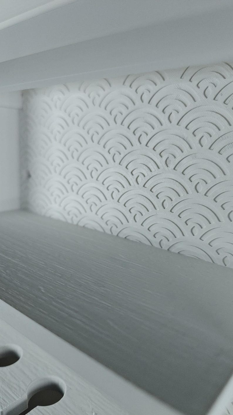 Peut inclure: Une &eacute;tag&egrave;re blanche dot&eacute;e d'un panneau arri&egrave;re avec un motif r&eacute;p&eacute;titif de demi-cercles en relief. La surface de l'&eacute;tag&egrave;re pr&eacute;sente une finition gris clair lisse. La structure comprend un cadre blanc avec des d&eacute;coupes circulaires.