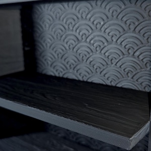Peut inclure: Une unit&eacute; de rangement gris fonc&eacute; dot&eacute;e d'une &eacute;tag&egrave;re &agrave; texture de grain de bois et d'un panneau arri&egrave;re orn&eacute; d'un motif en relief r&eacute;p&eacute;titif de demi-cercles superpos&eacute;s. La structure est faite d'un mat&eacute;riau gris fonc&eacute; mat avec des couches visibles.