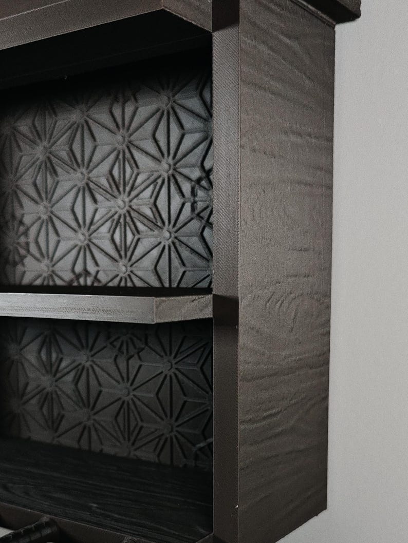 Peut inclure: Une &eacute;tag&egrave;re murale marron fonc&eacute; avec une finition en grain de bois textur&eacute; sur le cadre ext&eacute;rieur. Les panneaux arri&egrave;re des deux &eacute;tag&egrave;res visibles sont d&eacute;cor&eacute;s d'un motif g&eacute;om&eacute;trique en &eacute;toile r&eacute;p&eacute;titif dans une finition gris mat.