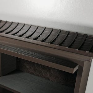 Peut inclure: Une &eacute;tag&egrave;re en bois brun fonc&eacute; dot&eacute;e d'une section sup&eacute;rieure con&ccedil;ue avec une structure de toit incurv&eacute;e et tuil&eacute;e. Le panneau arri&egrave;re pr&eacute;sente un motif g&eacute;om&eacute;trique en &eacute;toile, tandis que les &eacute;tag&egrave;res horizontales ont un grain de bois visible.