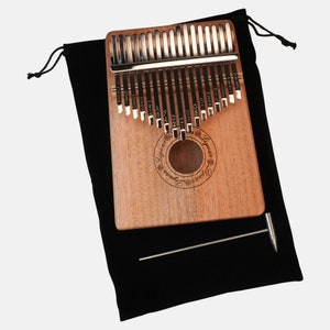 Puede incluir: Un kalimba de madera con una funda de transporte de terciopelo negro y una herramienta de afinaci&oacute;n de metal. El kalimba tiene un dise&ntilde;o circular con el texto "Lyrebird" y "Lyrebird" impreso en &eacute;l.