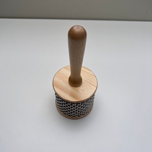 May include: A wooden shakers with a wooden handle and a metal bead surface.