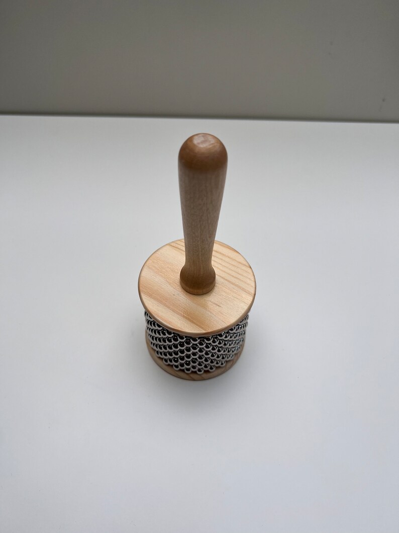 May include: A wooden shakers with a wooden handle and a metal bead surface.