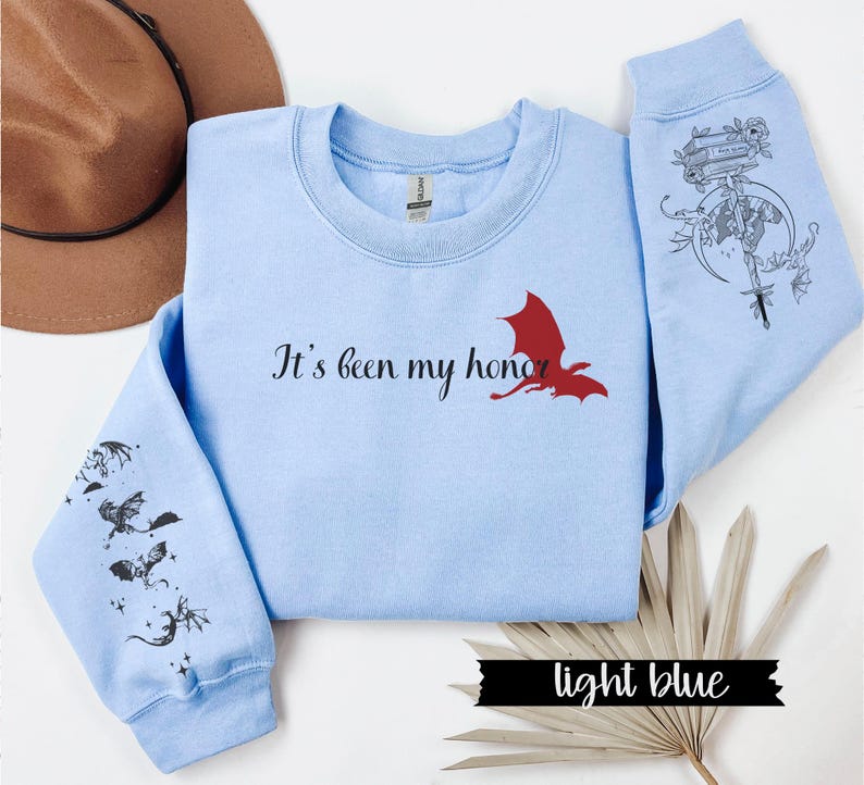 May include: Light blue sweatshirt with a red dragon graphic and the text "It's been my honor". The sleeves feature black dragon silhouettes.