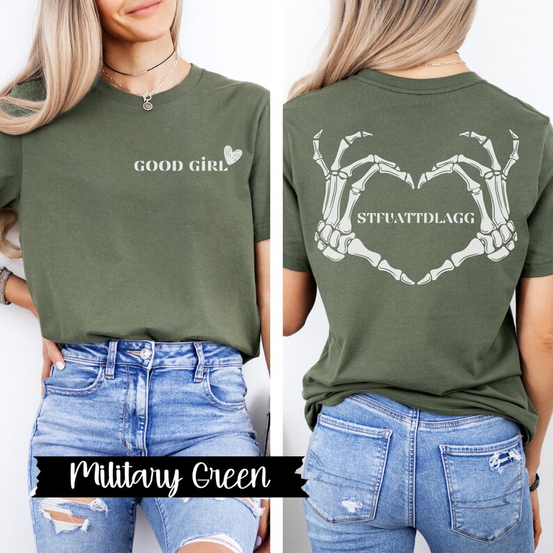 K&ouml;nnte beinhalten: Ein gr&uuml;nes T-Shirt mit dem Text "GOOD GIRL" und einem Herz auf der Vorderseite. Die R&uuml;ckseite des Shirts zeigt eine Skeletthand, die ein Herz mit dem Text "STFUATTDLAGG" formt.
