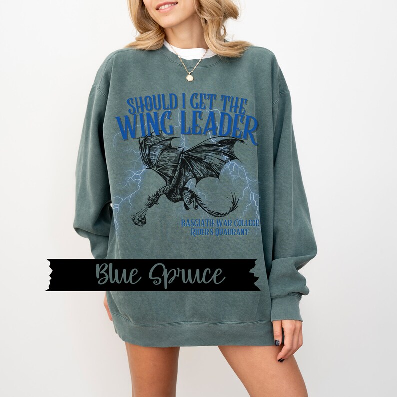 May include: A green sweatshirt with a blue graphic of a dragon with the text "Should I get the Wing Leader" and "Basgjath War College Riders Quadrant".
