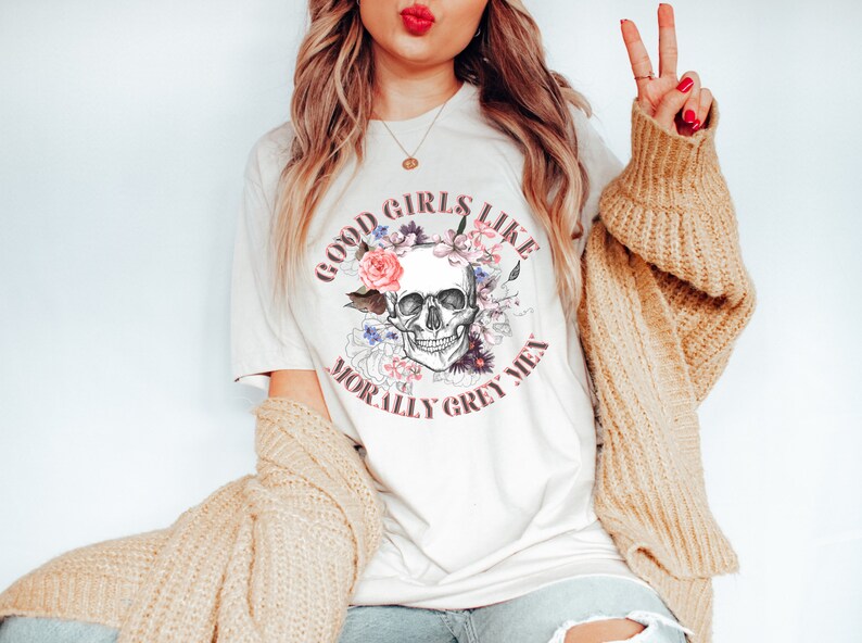 May include: White t-shirt featuring a floral skull graphic and the text "Good girls like morally grey men".