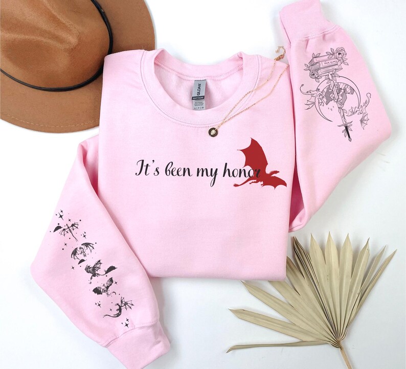 May include: Pink sweatshirt with a red dragon graphic and the text "It's been my honor". The sleeves have a black dragon design.
