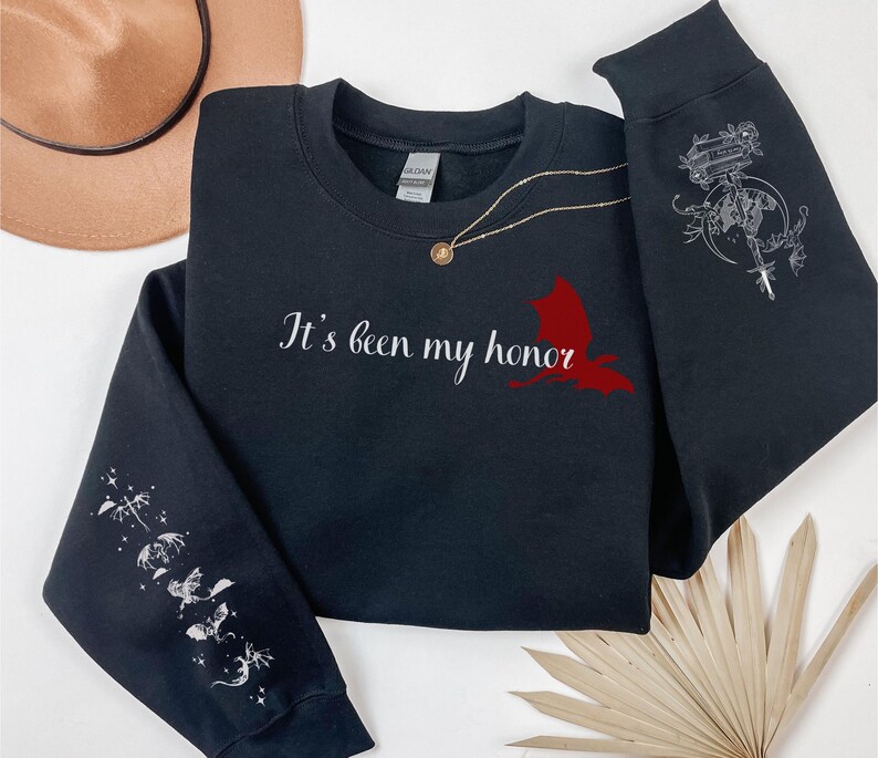 May include: Black sweatshirt with the text "It's been my honor" and a red bird graphic on the front. The sleeves have white graphic designs of birds and stars.