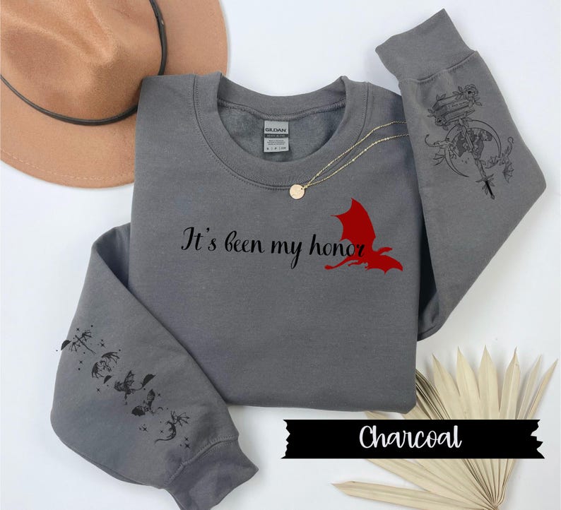 May include: A charcoal grey sweatshirt with a red dragon graphic and the text "It's been my honor". The sleeves have a black and white graphic of a dragon with a sword and a moon.