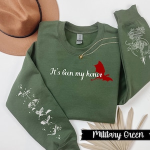 May include: A military green sweatshirt with the text "It's been my honor" and a red dragon graphic on the front. The sleeves feature white dragon designs.