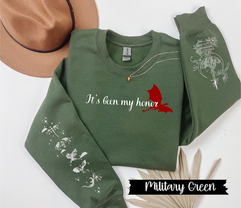 May include: A military green sweatshirt with the text "It's been my honor" and a red dragon graphic on the front. The sleeves feature white dragon designs.