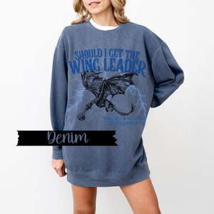 May include: A blue sweatshirt with a graphic print of a dragon and the text "Should I get the Wing Leader" in blue. The text "Basgiath War College Riders Quadrant" is printed in smaller font below the dragon.