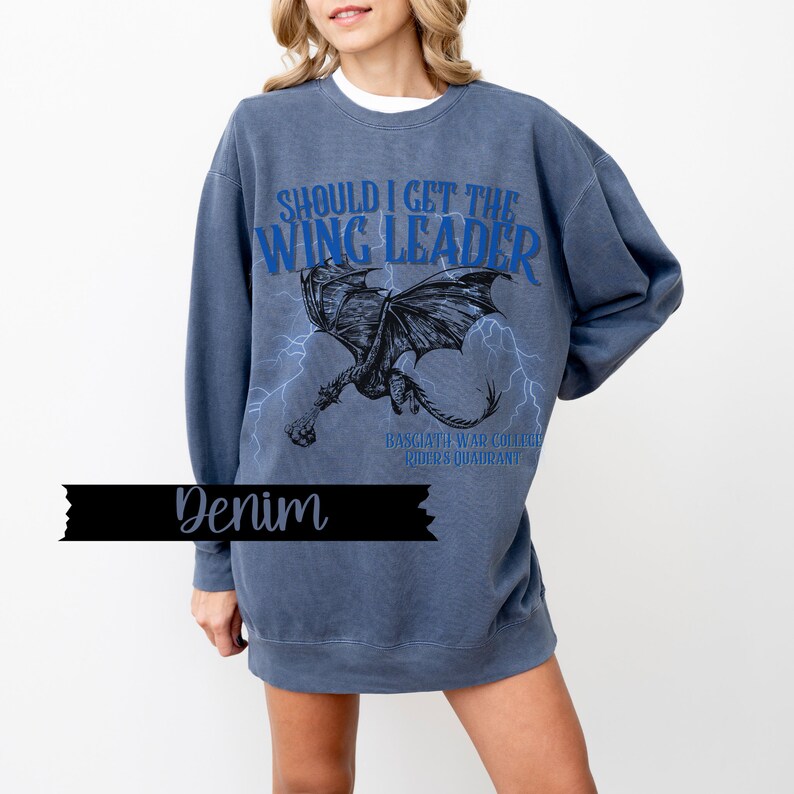 May include: A blue sweatshirt with a graphic print of a dragon and the text "Should I get the Wing Leader" in blue. The text "Basgiath War College Riders Quadrant" is printed in smaller font below the dragon.