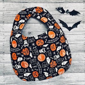 Peut inclure: Bavoir de bébé noir et orange sur le thème de Star Wars et d'Halloween. Le bavoir présente une variété d'images, notamment Dark Vador, des citrouilles et des chauves-souris. Le texte sur le bavoir est "These are not the treats you're looking for".