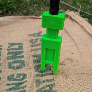 May include: A bright green plastic tent stake with a black metal top and the text "Big Stakes" printed on the top.