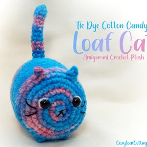May include: Tie Dye Cotton Candy Loaf Cat Amigurumi Crochet Plush. A crocheted cat plush toy with a blue and pink tie-dye pattern. The cat has a round body and a long tail.