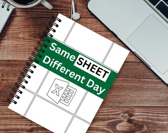 May include: A spiral-bound notebook with a white cover featuring a grid design and the Microsoft Excel logo. The notebook has the text "Same SHEET Different Day" on a green banner. A laptop, coffee cup, and earbuds are also visible.