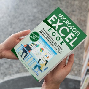 A person holding an Excel beginners book authored by Harjit Suman with both hands.