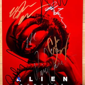 May include: A red movie poster with the title "Alien: Romulus" in white letters. The poster features a close-up of a Xenomorph alien's hand. The poster is signed by the director, Fede Alvarez, and the producer, Ridley Scott.