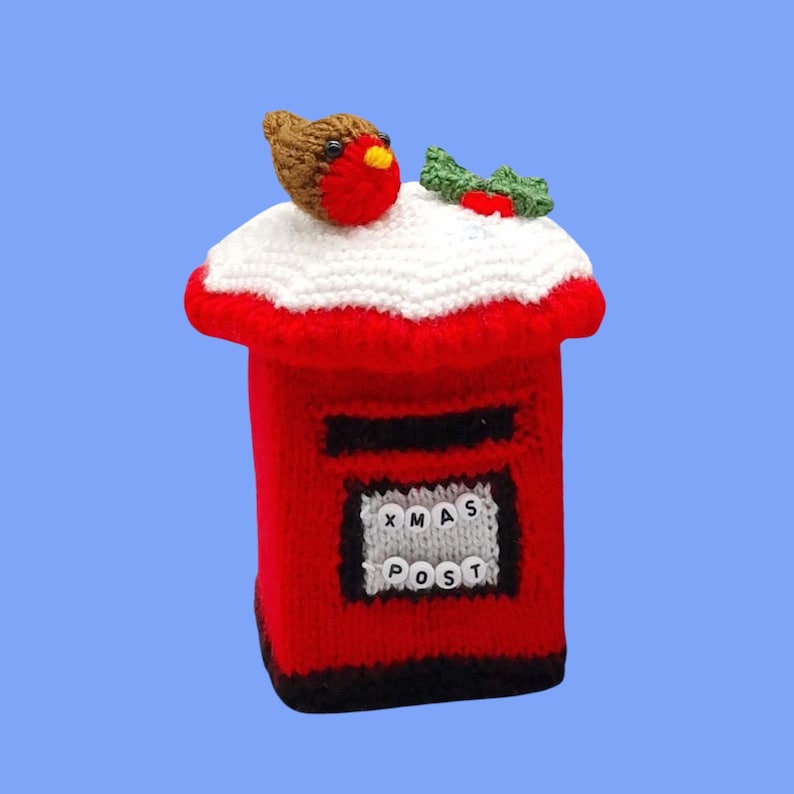 May include: A red knitted post box cover featuring a white snow-like top, a brown robin with a red chest, and green holly leaves. The front displays a grey panel with white beads spelling out XMAS POST in black letters against a red base.