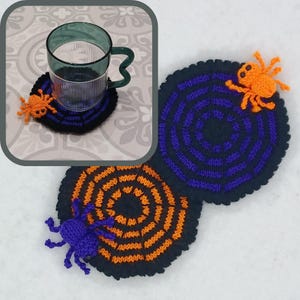 May include: Two crocheted coasters with a spider web design. One coaster is black with purple circles and an orange spider. The other coaster is black with orange circles and a purple spider.