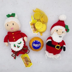May include: A knitted Mrs Claus doll in a red dress with a white apron, a knitted Santa Claus doll in a red suit with a white beard, a mesh bag of gold foil-wrapped chocolate coins, and a round Terry's chocolate orange in gold foil wrapping.