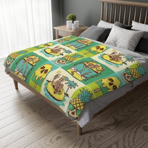 May include: A green, yellow, and blue patterned throw blanket with a skeleton design. The blanket features a repeating pattern of skeletons on surfboards, pineapples, and ice cream cones. The text "Salty Iced Memories" is printed on the blanket.