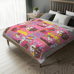May include: Pink and brown fleece throw blanket with a repeating pattern of cartoon characters, donuts, cupcakes, and the words "Yum" and "Party".