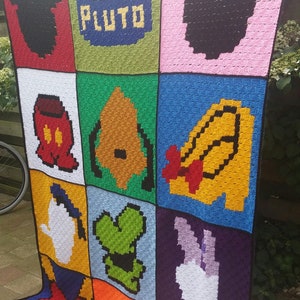 May include: A colorful crocheted blanket featuring various Disney characters, including Mickey Mouse, Minnie Mouse, Pluto, and Donald Duck. The blanket is made up of individual squares, each featuring a different character.