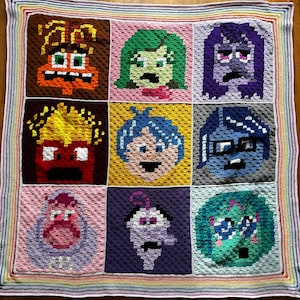 Puede incluir: Una manta de ganchillo con los personajes de la película Inside Out. La manta está compuesta por nueve cuadrados, cada uno con un personaje diferente: Alegría, Tristeza, Ira, Miedo, Asco, Bing Bong y algunos otros. La manta está bordeada con un ribete de colores arcoíris.