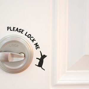 May include: A white door with a silver door knob and a black cat sticker that says "Please lock me".