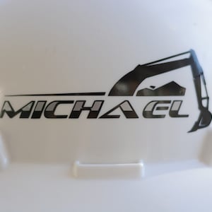 May include: White hard hat with a black and grey logo that says "MICHAEL" and a silhouette of an excavator.