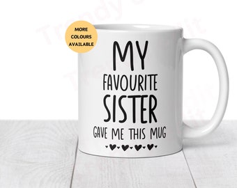 May include: White ceramic mug with black text that reads "My Favourite Sister Gave Me This Mug" with five small black hearts below the text.