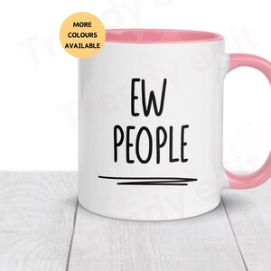 May include: White ceramic mug with a pink rim and handle. The mug has black text that reads "EW PEOPLE" with a black line underneath.