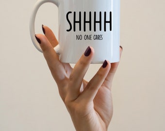 May include: White ceramic mug with a black inscription that reads "SHHHH NO ONE CARES".